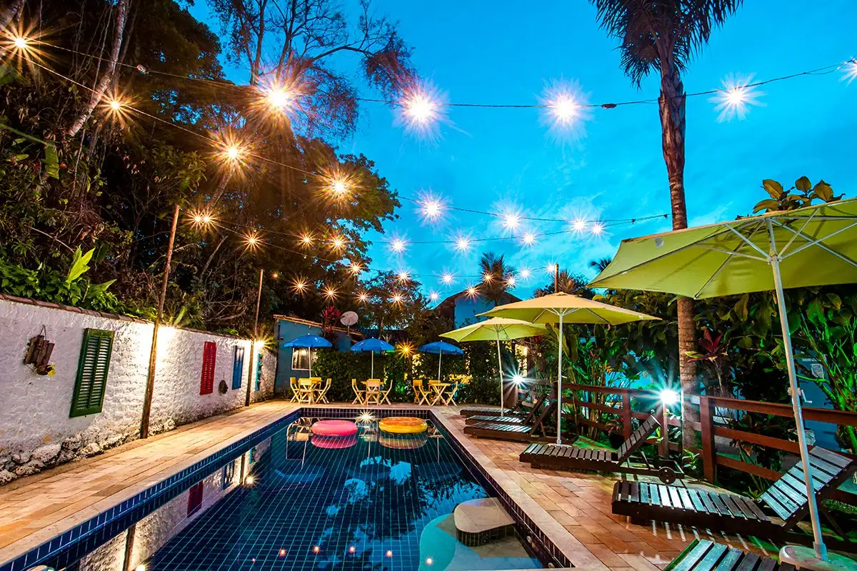 Piscina aquecida da pousada ao entardecer, com varal de luzes acesas
