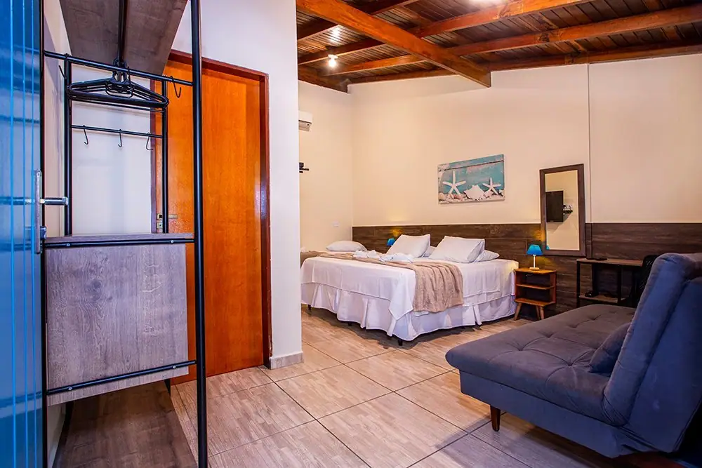 Suíte Deluxe da Pousada Villa Blu, em Maresias, com cama king e sofá azul