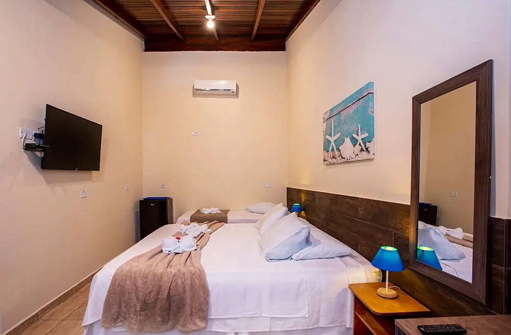 Cama king da Suíte Deluxe com espelho e smart TV
